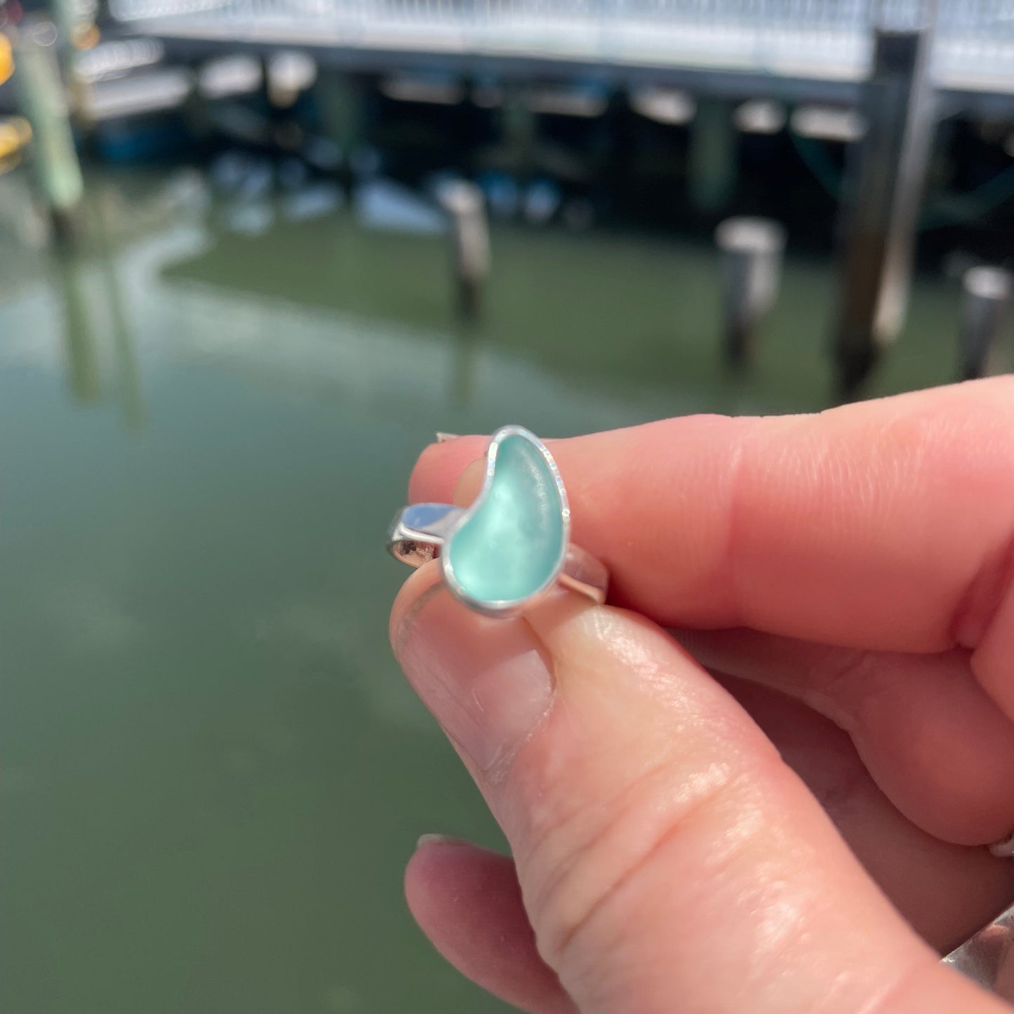 Hand holding a small turquoise stone with a blurred background